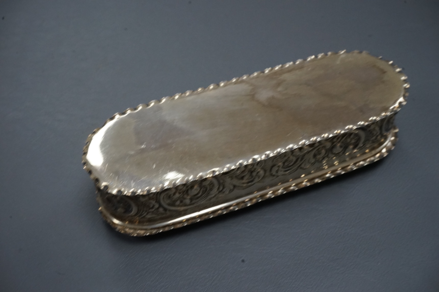 An early 20th century repousse silver dressing table tray by William Comyns & Sons Ltd, London, 1901, 25.1cm, together with a matching oval trinket box, London, 1900, 16.6oz (a.f.).